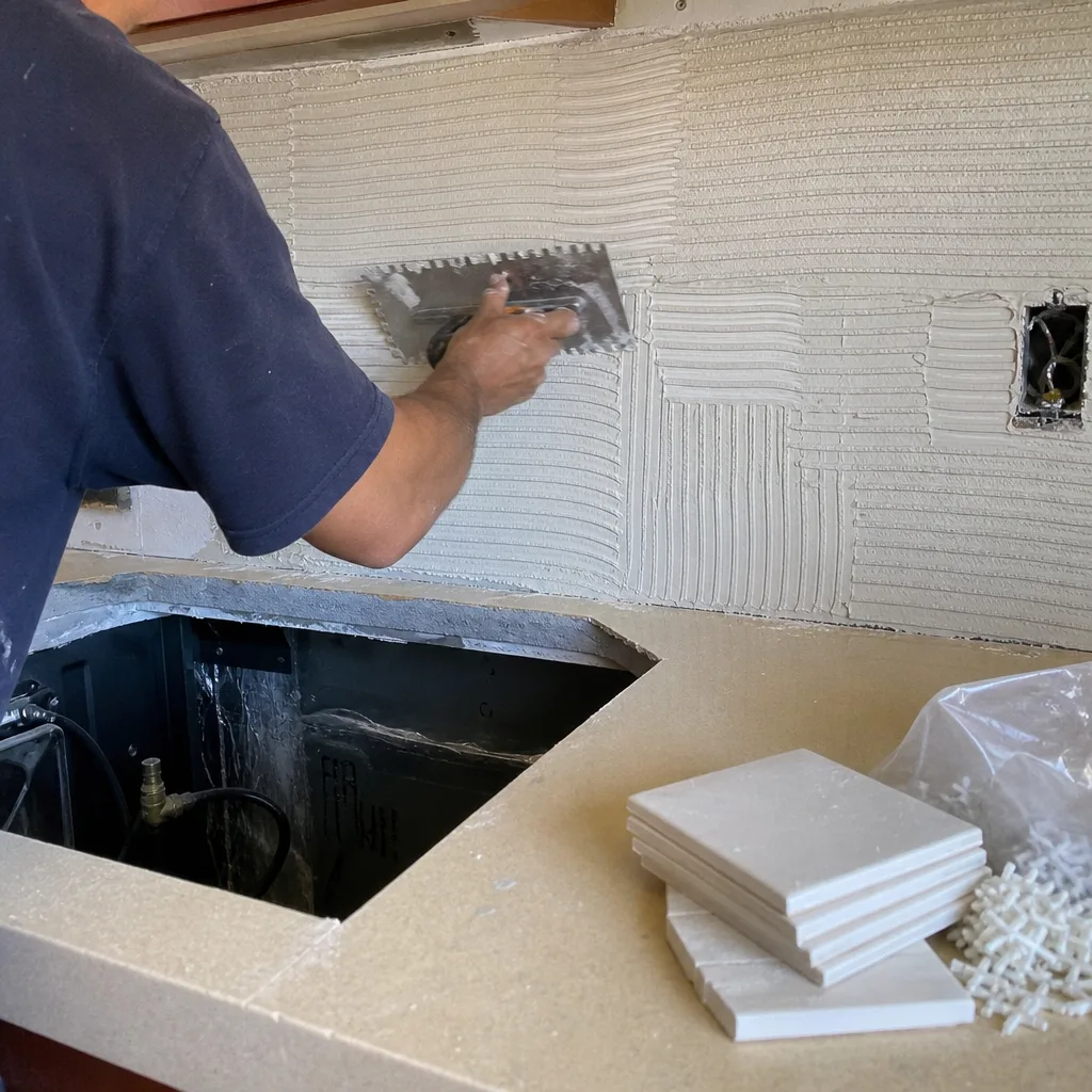 Professional contractor applying mortar to a kitchen backsplash for tile installation